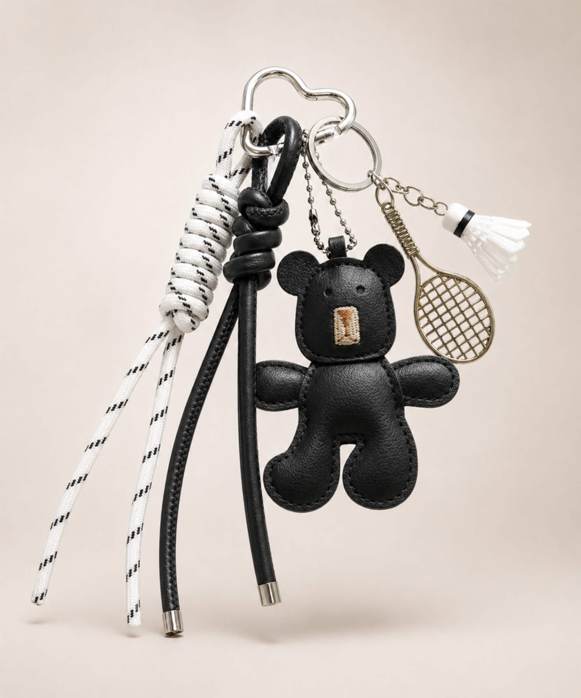 Black bear PU leather bag charm keychain with a badminton racket charm and shuttlecock charm on a neutral background.
